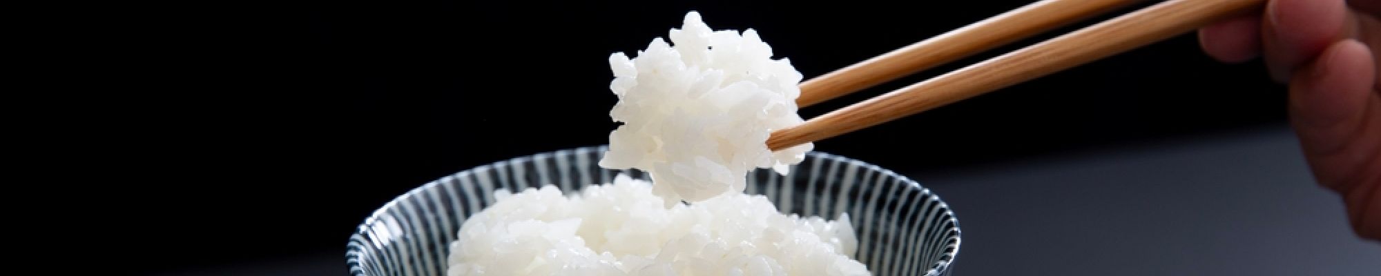 Chopsticks picking up white rice from a bowl